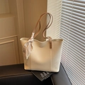 Off-white lychee grain tote bag with brown straps and floral scarf on a black stand - White