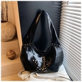 Vue détaillée des clous en forme d'étoile sur un sac hobo en cuir verni noir brillant - Noir