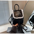 Detail eines schwarzen Mini-Rucksacks mit weißen Rüschen und gesticktem Schriftzug - Einheitsgröße / Schwarz