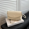Elegante borsa a tracolla beige con texture litchi su uno sfondo minimalista raffinato - Bianco