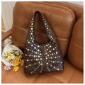 Détail d'un sac hobo marron vintage avec des rivets argentés sur un canapé en cuir - Marron