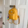 Détail d'un mini sac à dos en cuir PU jaune vif avec zips argentés sur un crochet de porte - Jaune avec Pendentif