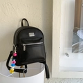 Détail de sac à dos en cuir PU grainé noir avec logo argenté et charm coloré LOVELY - Noir Avec Pendentif