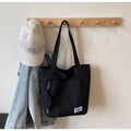 Détail du sac fourre-tout en toile noire avec une petite pochette et une étiquette blanche - Noir