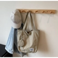 Detail of khaki canvas tote bag with small round coin purse and white woven label - Khaki