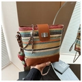 Détail d'un sac seau en paille à rayures colorées avec base en cuir et breloque fraise - Marron avec pendentif