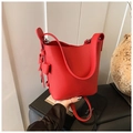 Détail du sac seau rouge montrant le cuir grainé de lychee et le nœud décoratif en cuir - Rouge