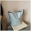 Light blue crocodile pattern bucket bag with adjustable strap on white lifestyle prop - Blue
