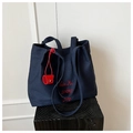 Dettaglio della borsa tote in tela blu navy con ricamo rosso e mini ciondolo abbinato - Blu