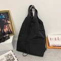 Close-up of black nylon drawstring tote bag with wrinkled texture and wide woven handles - White