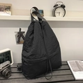 Detail of a black nylon drawstring tote bag with dual handles on a minimalist wooden desk - Black