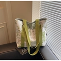 Dettaglio della borsa tote in tela con stampa di bambù verde su un divano in pelle nera - Verde