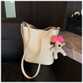 Detail of cream bucket bag featuring a plush puppy charm and embossed brand logo - Beige With Charm
