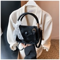 Detail of black mini handbag with elegant white lace bow and gold-tone hardware buckles - Black