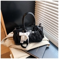 Detail of black patent leather handbag with silver lock and pearl lace bow accessory - Black
