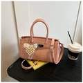 Detailed macro view of pink pleated leather handbag with pearl heart charm and metal lock - Pink