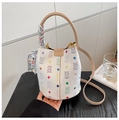 Detailed view of white bucket bag featuring colorful bear patterns and silk scarf decor - White