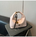 Detailed macro view of pink patent leather handbag with gold buckle and bell charm - With Pendant / Pink