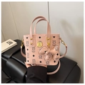 Detail of pink faux leather bag showing litchi texture and golden brand logo plate - Pink