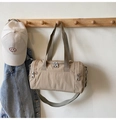 Detail of a beige nylon cylinder travel bag hanging on a hook with a baseball cap - Khaki