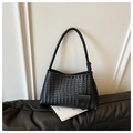 Detailed view of black woven hobo shoulder bag with textured leather on a dark sofa - Black