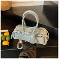 Détail d'un sac cylindre en denim bleu clair avec clous argentés et nœud décoratif - Bleu