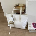 Détail du sac cabas blanc gaufré crocodile avec breloque ours mignon sur parquet en bois - Avec Pendentif / Blanc