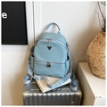 Détail d'un sac à dos bleu clair à texture litchi avec sangle sur valise argentée - Bleu