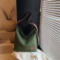 Olive green canvas hobo bag with adjustable brown leather strap in a minimalist setting - Green