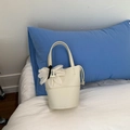 Sac seau beige avec texture litchi et charme floral posé sur un lit blanc - Blanc