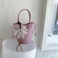 Pink lychee grain leather bucket bag with top handle and white floral pendant detail - Pink