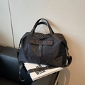 Sac de voyage noir en nylon imperméable avec bandoulière amovible sur un canapé - Noir