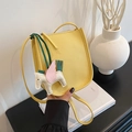 Minimalist bright yellow lychee leather bucket bag with white pegasus charm on white books - Yellow
