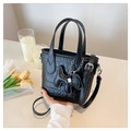Détail d'un mini sac noir à texture croco avec un charm élégant sur une surface épurée - Avec Pendentif / Noir