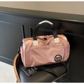 Borsa da viaggio rosa impermeabile con manici neri e tracolla sopra uno sgabello - Rosa