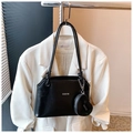 Détail d'un sac seau noir verni avec bandoulière nouée et mini pochette en cœur - Noir