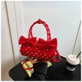 Detalle del bolso cilíndrico rojo con lunares, lazos grandes dobles y textura de charol fino - Rojo