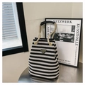 Close-up of black and white striped canvas bucket bag with rope handle and metal logo - Black