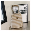 Detail of striped canvas bucket bag showing thick rope handle and metal logo plaque - Khaki