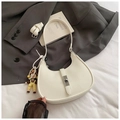 White lychee leather hobo bag with silver buckle and doll charm in aesthetic setting - White with Pendant