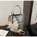 Detail of silver metallic bucket bag with white flower pendant and red drawstring closure - Silver