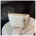 Detail of white quilted crossbody bag with silver chain strap on a designer magazine - Off White