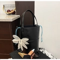 Minimalist black bucket bag with a glossy pleated texture and a floral charm detail - Black