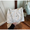 Detail of white quilted bucket bag featuring silver studs and rhinestone star accent - Off White