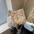 Quilted white bucket bag with silver studs and chain strap shown in a hand-held view - Off-white