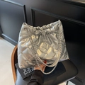 Quilted silver bucket bag with star rhinestones and metal chain strap on a black chair - Silver
