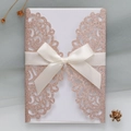 Detail of rose gold glitter laser-cut invitation with elegant white satin bow ribbon - Apple Gold