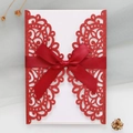 Close-up of laser-cut red glitter wedding invitation with elegant satin bow detail - Red