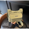 Close-up of light green crossbody bag with YOU JI BEAR label and wide fabric shoulder strap - Green