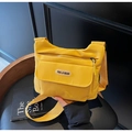 Detailed close-up of a bright yellow nylon crossbody bag on a dark leather chair - Yellow